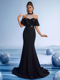 Elegant black beaded halter mermaid evening gown with sheer tulle sleeves and rhinestone bodice for formal gala or prom night.