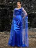 Woman wearing a Royal Blue floor-length satin evening gown with floor-length sheer cape sleeves and beaded embroidery on the neckline.
