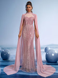 Blush rose sequin mermaid evening gown featuring a sheer high neck, heart-shaped bodice, and a long flowing cape for formal weddings or galas.