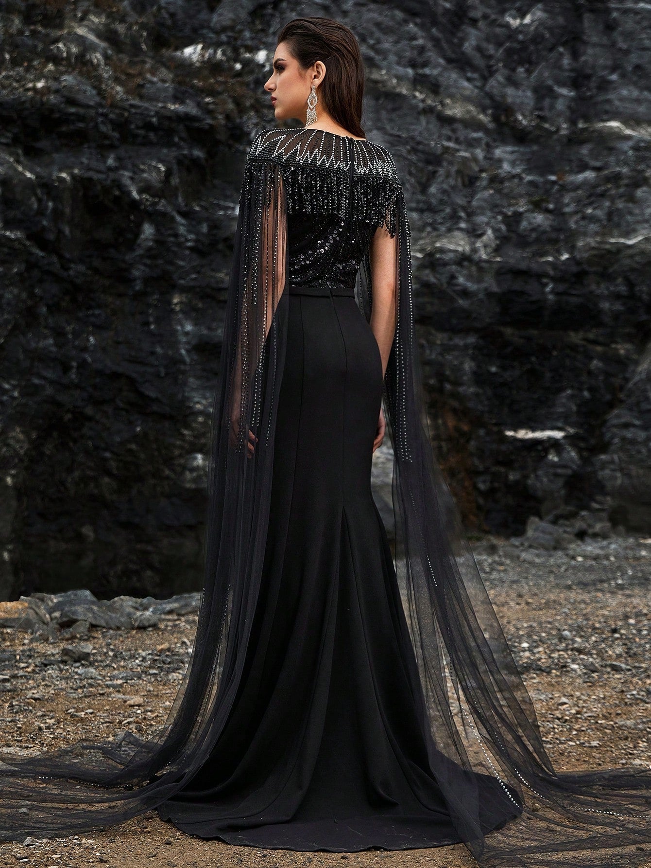 Luxury black beaded mermaid evening gown featuring a glamorous sheer tulle cape, intricate crystal fringe detailing on the neckline, and sparkling long sleeves for formal galas or red carpets.