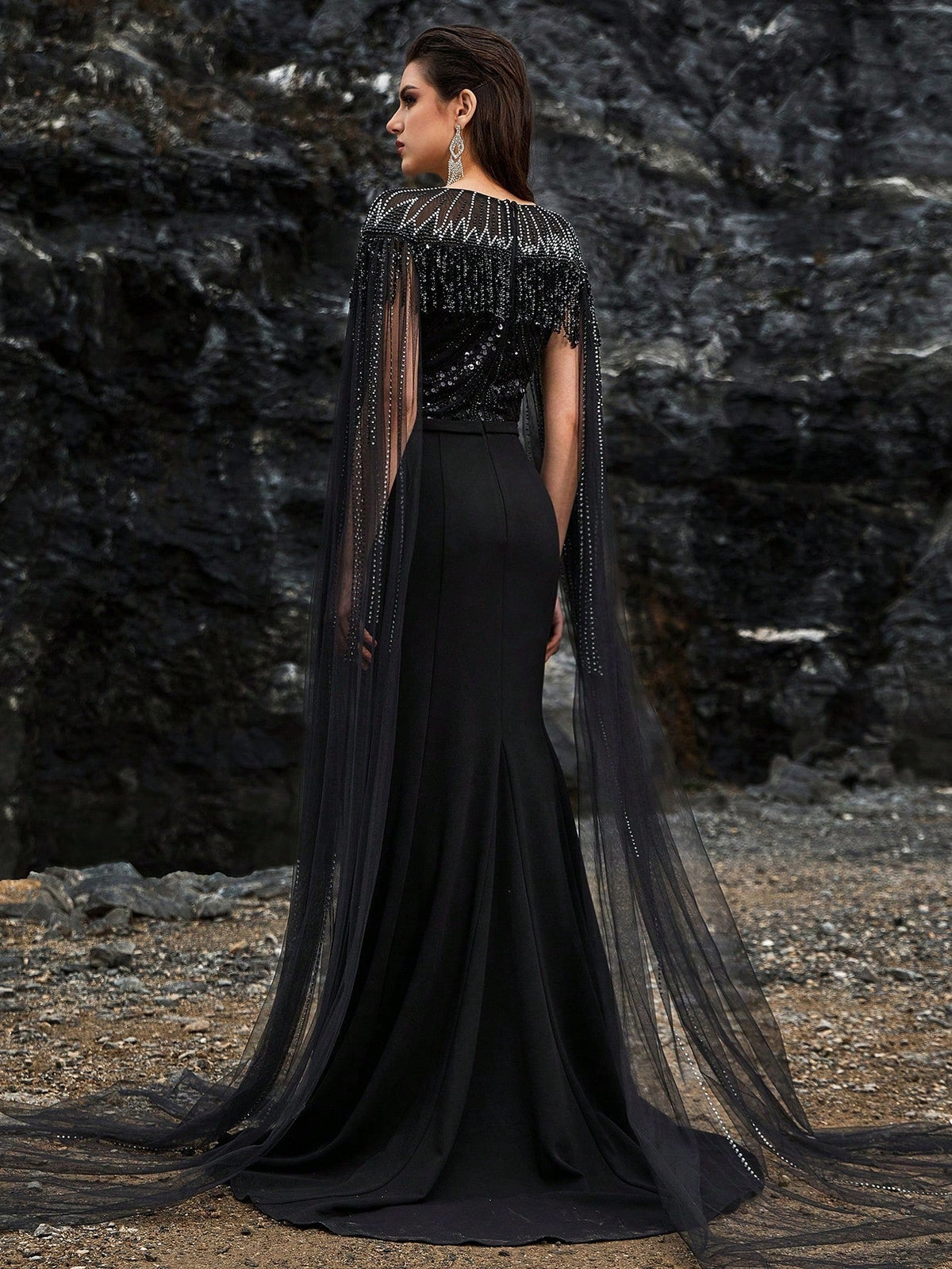 Luxury black beaded mermaid evening gown featuring a glamorous sheer tulle cape, intricate crystal fringe detailing on the neckline, and sparkling long sleeves for formal galas or red carpets.