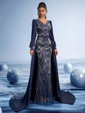 Model wearing a midnight blue evening gown featuring intricate silver metallic embroidery, long bishop sleeves, and a dramatic floor-length cape.