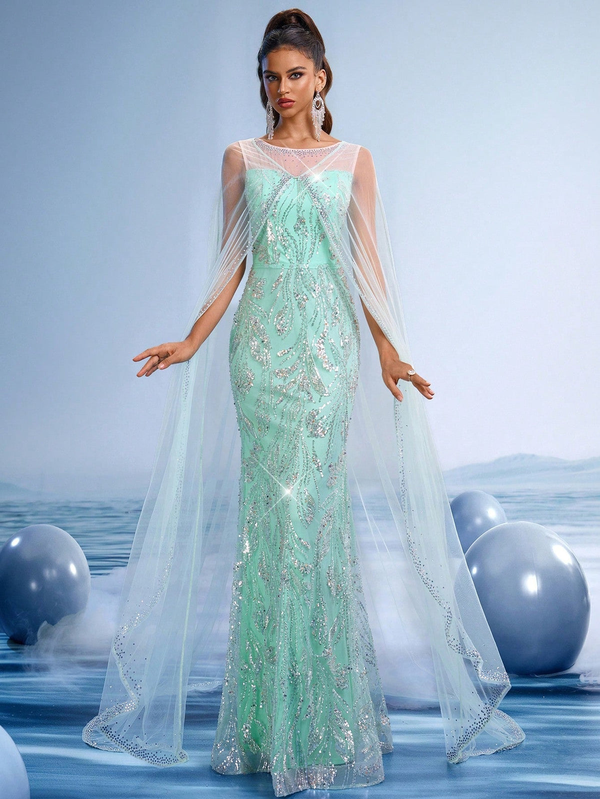 Mint green sequin mermaid evening gown featuring an illusion high neckline and elegant sheer flowing cape sleeves for formal galas or weddings.