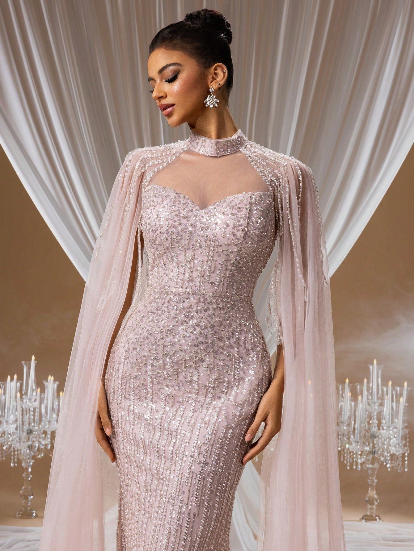 Woman wearing a [Soft Blush Pink Sequin Embroidered Mermaid Evening Gown](https://admin.shopify.com/store/anozara-2/products?selectedView=all&after=eyJsYXN0X2lkIjoxMDA5OTA2NjMwNjg1MSwibGFzdF92YWx1ZSI6IjIwMjYtMDEtMDggMDU6NTc6MzEuMDAwMDAwIn0%3D&start=NTE%3D) featuring a sheer high-neck bodice, floor-length cape sleeves, and intricate shimmering sequin details in an elegant gala setting.